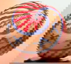 69424 BB Marbles: Nadine Macdonald Flag: CONTEMPORARY HANDMADE, Nadine Macdonald. Flag. Handmade and handpainted china. Nadine makes here own blank marbles. White background. Spiral of red lines edged by blue and spiral of blue stars. Signed