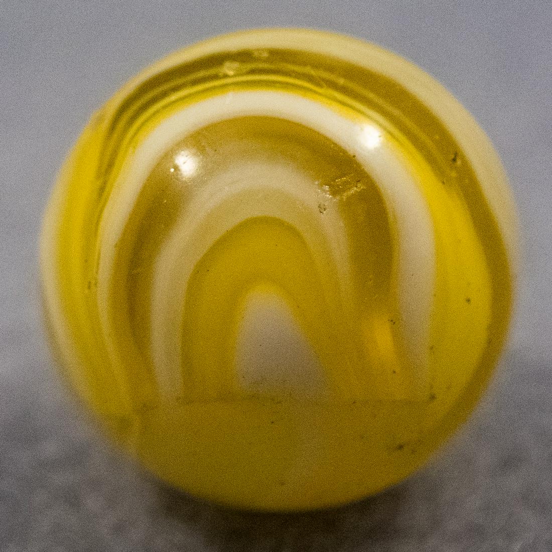 Marbles: CHRISTENSEN AGATE COMPANY, Slag. 19/32". Near Mint(+) (8.9).: CHRISTENSEN AGATE COMPANY, Slag. Electric yellow Slag. Transparent electric yellow base with opaque white swirling. Single seam example. Under a black light it glows orange and red! A couple pinpricks