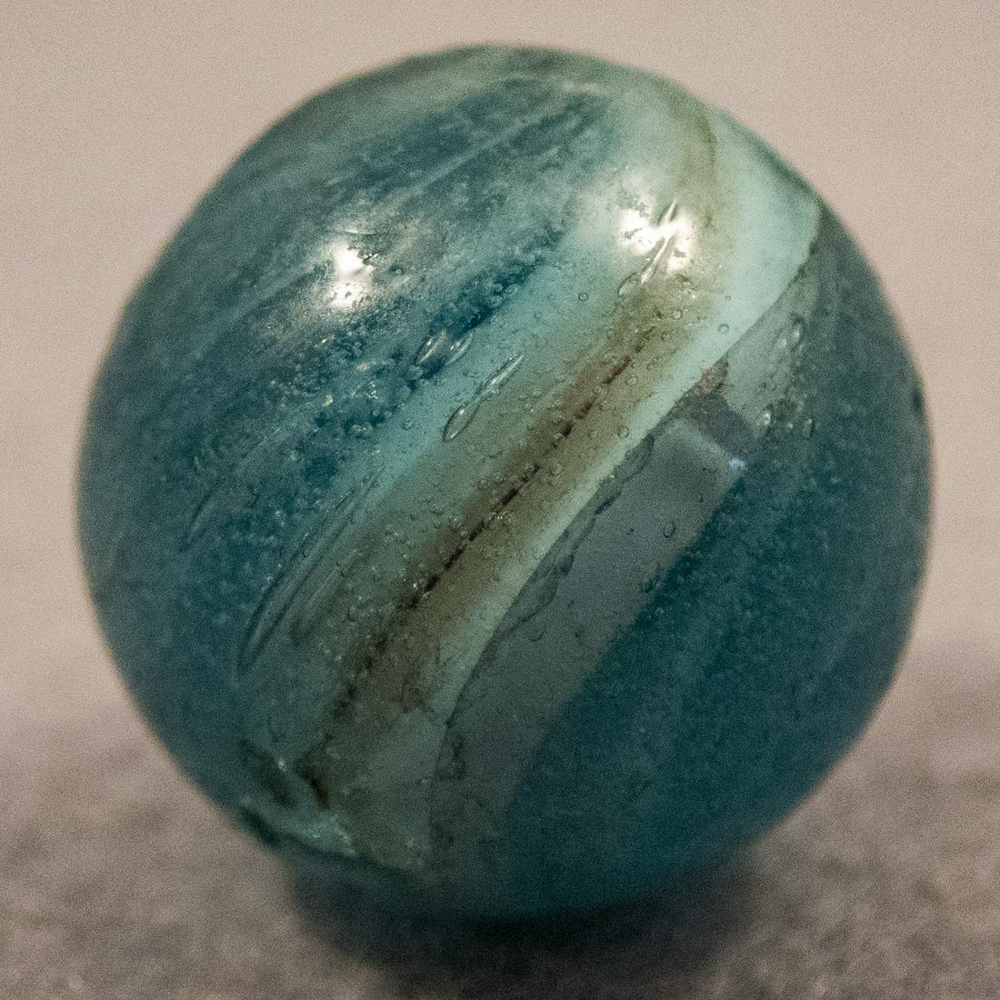 Marbles: END OF DAY, Mist. 23/32". Mint(-) (9.2).: END OF DAY, Mist. Very unusual marble. Transparent teal base filled with tons of tiny air bubble seeds. Filled with stretched bands of white. Some very light pocket wear. Germany, circa 1860-1920. 23/