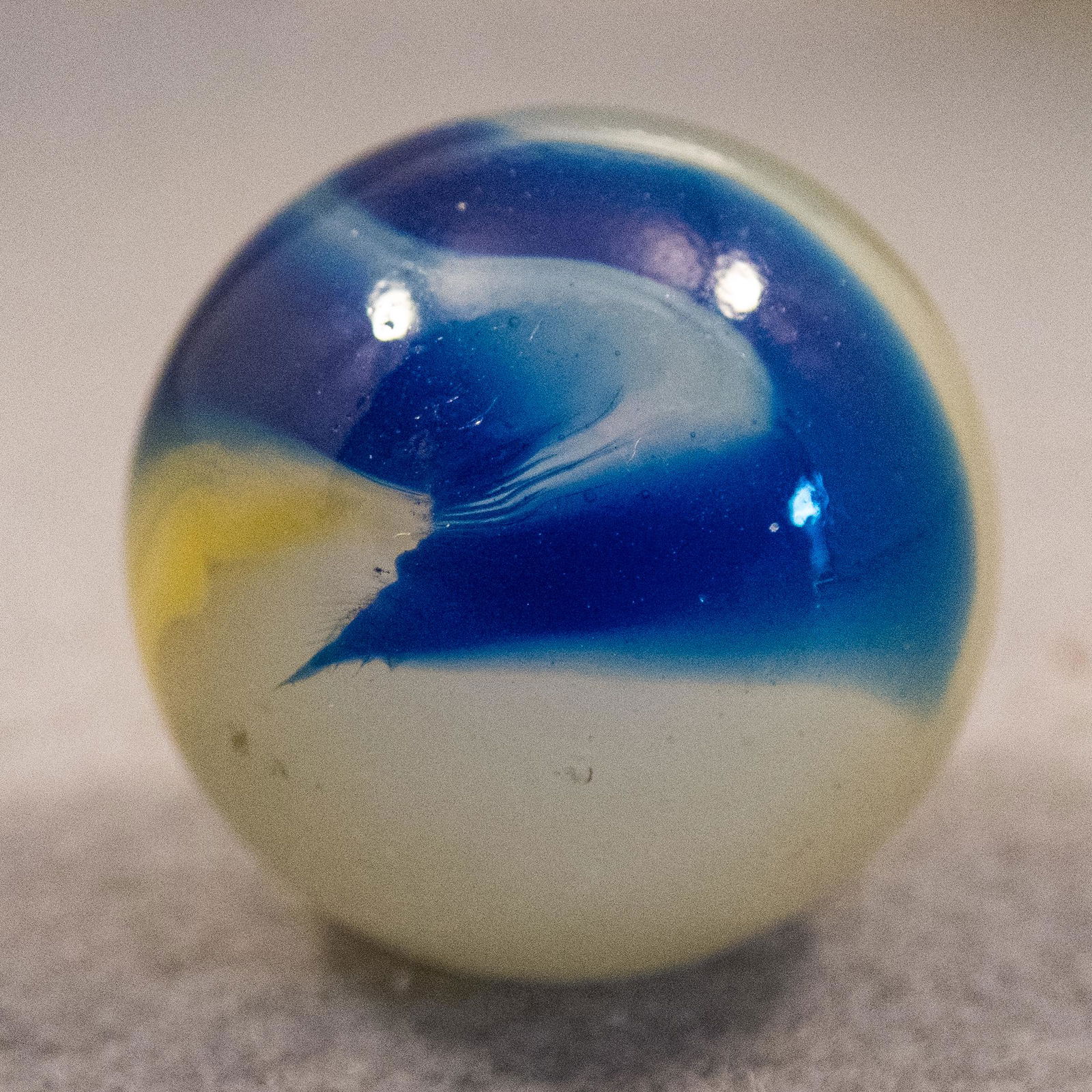 Marbles: AKRO AGATE COMPANY, Corkscrew. 15/16". Mint(-) (9.2).: AKRO AGATE COMPANY, Corkscrew. Transluent milky white base. Spiral of opaque yellow and two spirals of translucent blue. Two tiny manufacturing pits. Clarksburg WV, circa 1925-1935. 15/16". Mint(-) (9