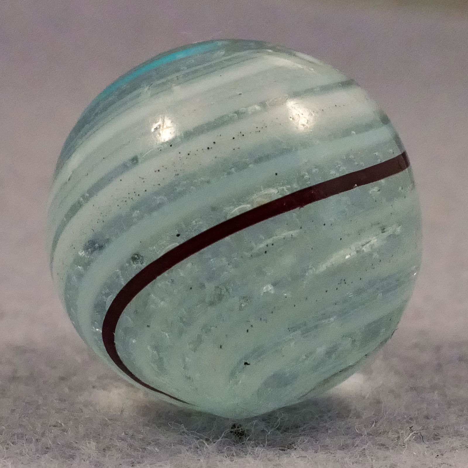 Marbles: OTHER, Banded Transparent. 25/32". Mint(-) (9.0).: Marbles: OTHER, Banded Transparent. Clear bubble filled base. Surface has stretched bands of semi-opaque white, opaque aqua and opaque black. A couple tiny manufacturing pits. Germany, circa 1860-1920