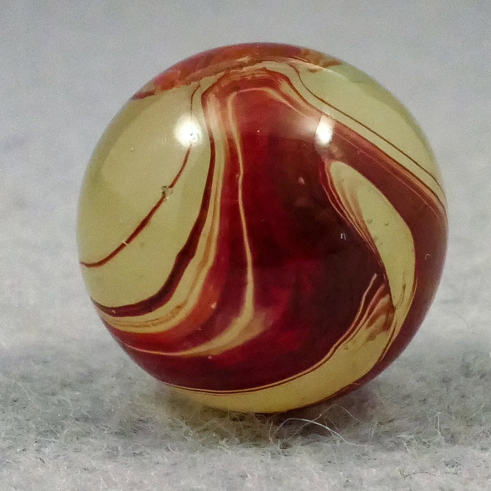 Marbles: AKRO AGATE COMPANY, Lemonade Oxblood. 19/32". Mint(-) (9.0).: AKRO AGATE COMPANY, Lemonade Oxblood. Fluorescent Ade base with nice rich oxblood swirls on it. One tiny sparkle. Clarksburg WV, circa 1925-1935.19/32". Mint(-) (9.0).