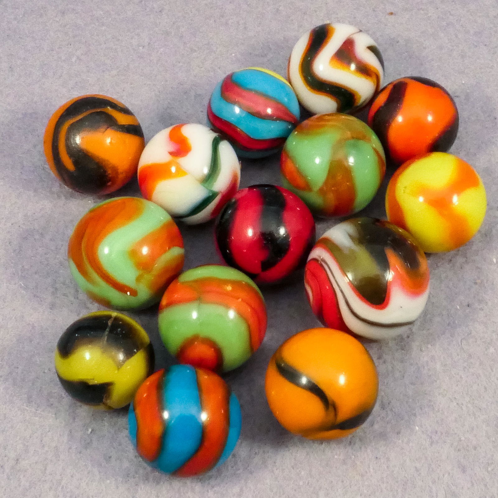 Marbles: PELTIER GLASS COMPANY, National Line Rainbo. 14 marbles.: PELTIER GLASS COMPANY, National Line Rainbo. Lot of fourteen marbles. Wide variety of National Line Rainbos, including a Superman. All have damage. Ottawa IL, circa 1925-1935. 19/32" to 3/4". Near Min