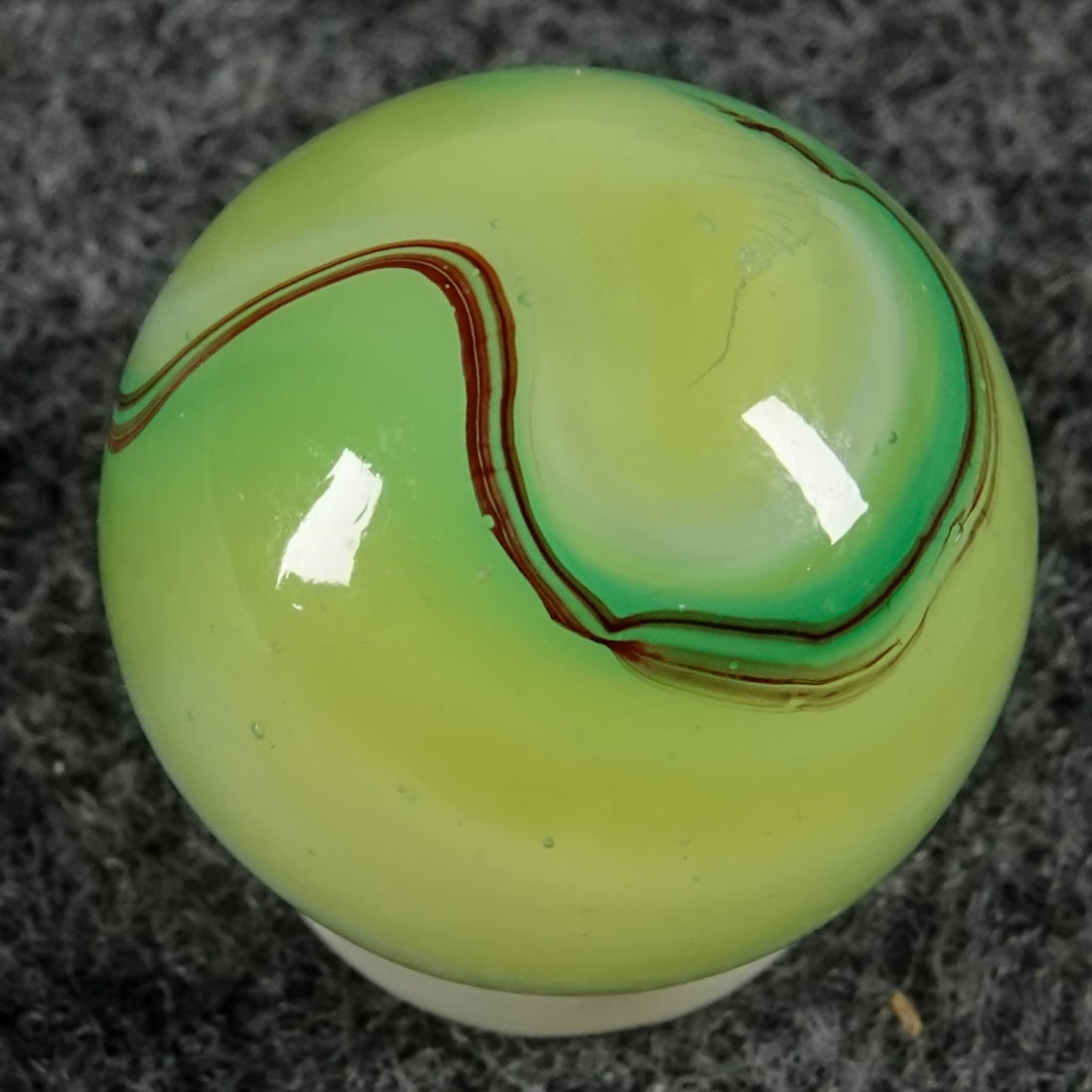 AKRO AGATE COMPANY, Limeade Oxblood. 21/32". Mint (9.5).: AKRO AGATE COMPANY, Limeade Oxblood. Fluorescent Ade base with semi-opaque white swirls, translucent green swirl and oxblood on the top. A very tiny manufacturing spot on it. Clarksburg WV, circa 1925