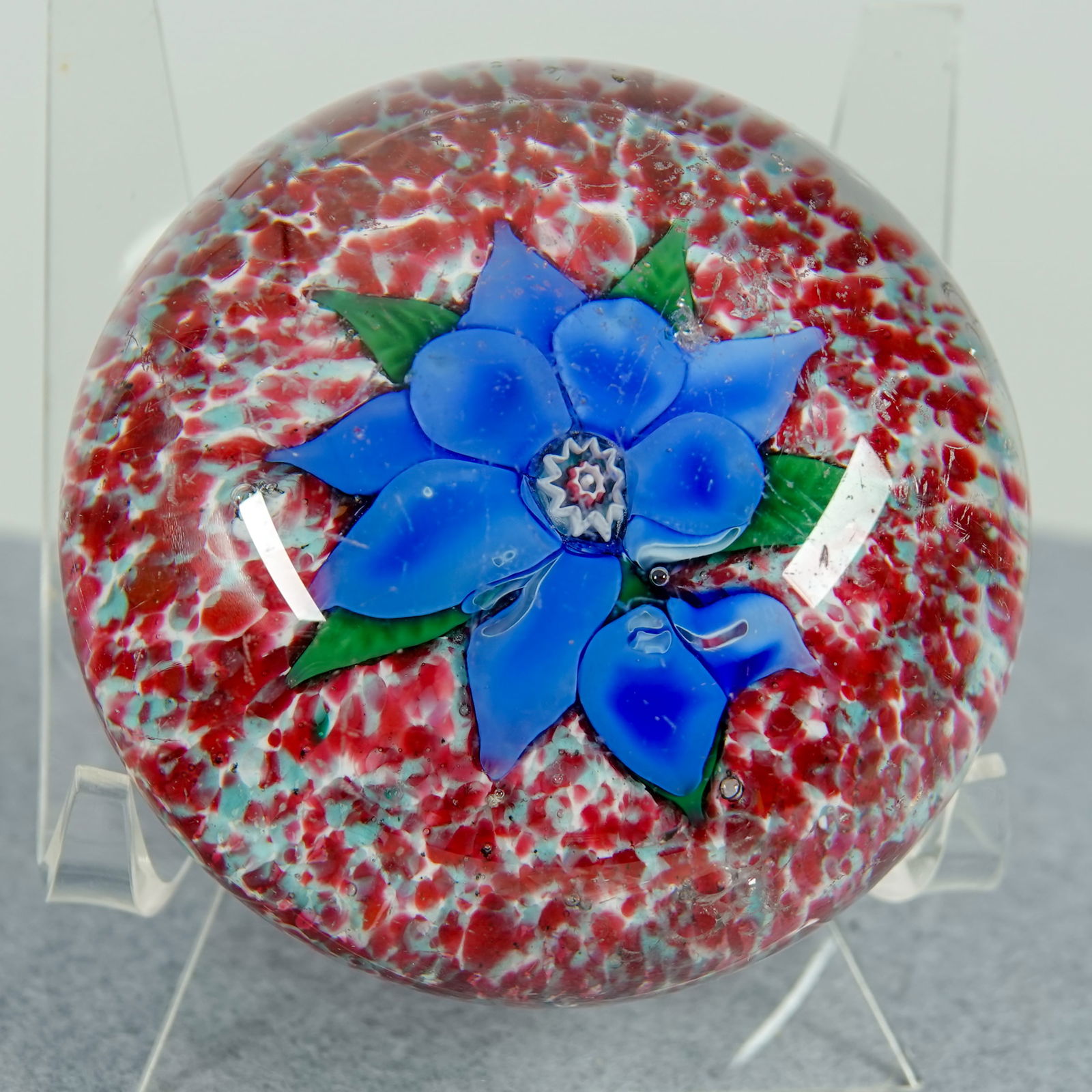 PAPERWEIGHT, Boston and Sandwich Glass. Poinsettia.: PAPERWEIGHT, Boston and Sandwich Glass. Antique Blue Poinsettia paperweight. Blue flower with green leaves on red and white jasper background. Very small chip on the crown, several barely visible subs