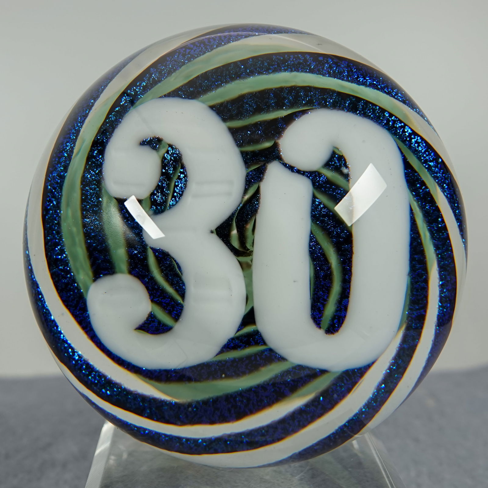 PAPERWEIGHT, Epiphany Studio.: PAPERWEIGHT, Epiphany Studio. Numeral "30" on dichroic swirl background. Signed on base "Epiphany 2020". 3-1/2" width, 3-1/8" height. Mint.