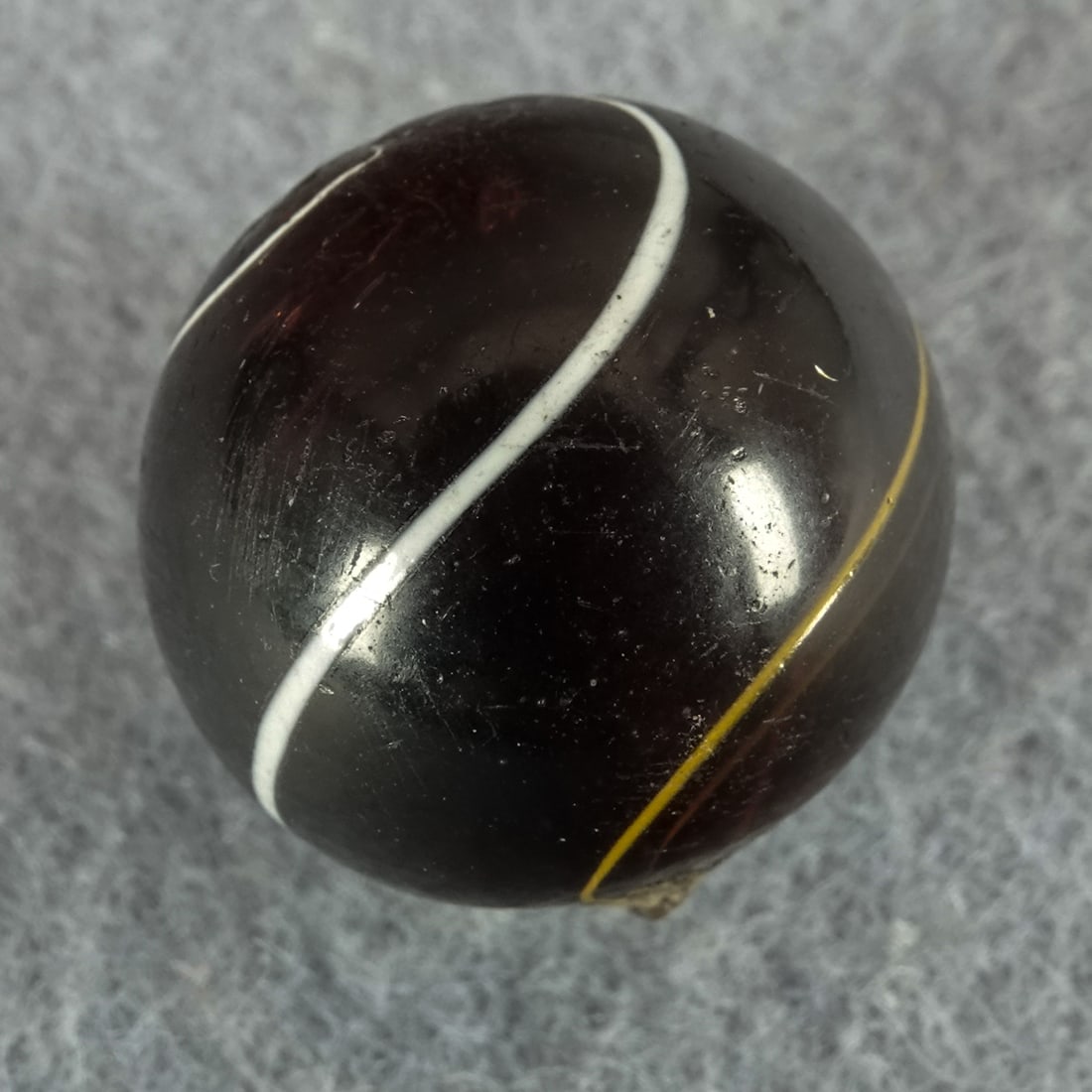 OTHER HANDMADE, Indian. Transparent. 3/4". Mint(-) (9.0).: OTHER HANDMADE, Indian. Transparent currant red base. Three white strands on the surface. A little light pocket wear. Germany, circa 1860-1920. 3/4". Mint(-) (9.0).