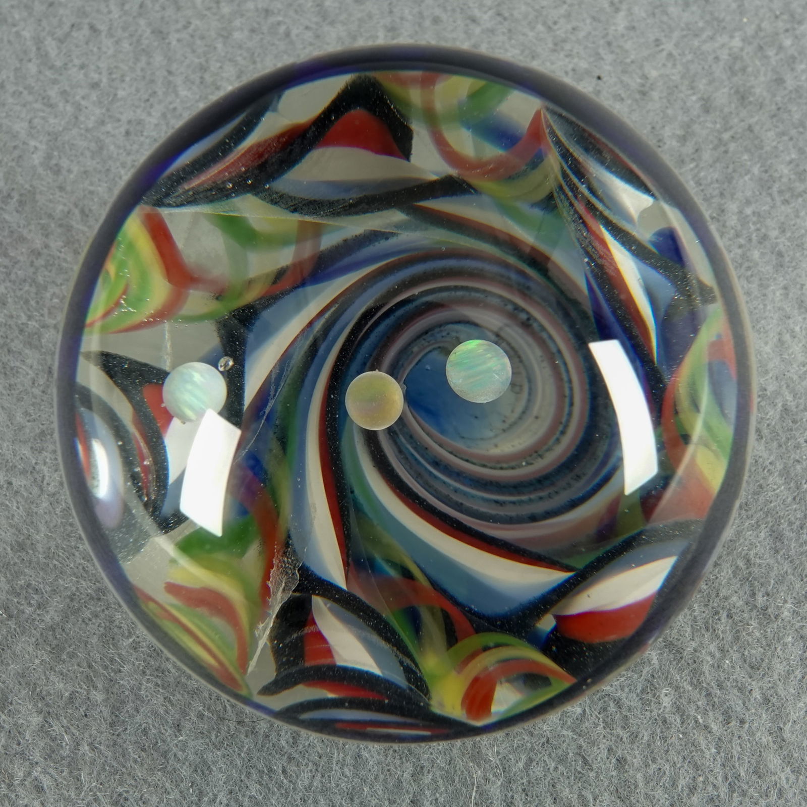 CONTEMPORARY HANDMADE, Unsigned. 1-15/16". Mint (9.9).: CONTEMPORARY HANDMADE, Unsigned. Vortex created of ribbon canes. Three opal planets being drawn down into the vortex. The back of the marble is matte finished (abrasive grinding) with a mask of stars.