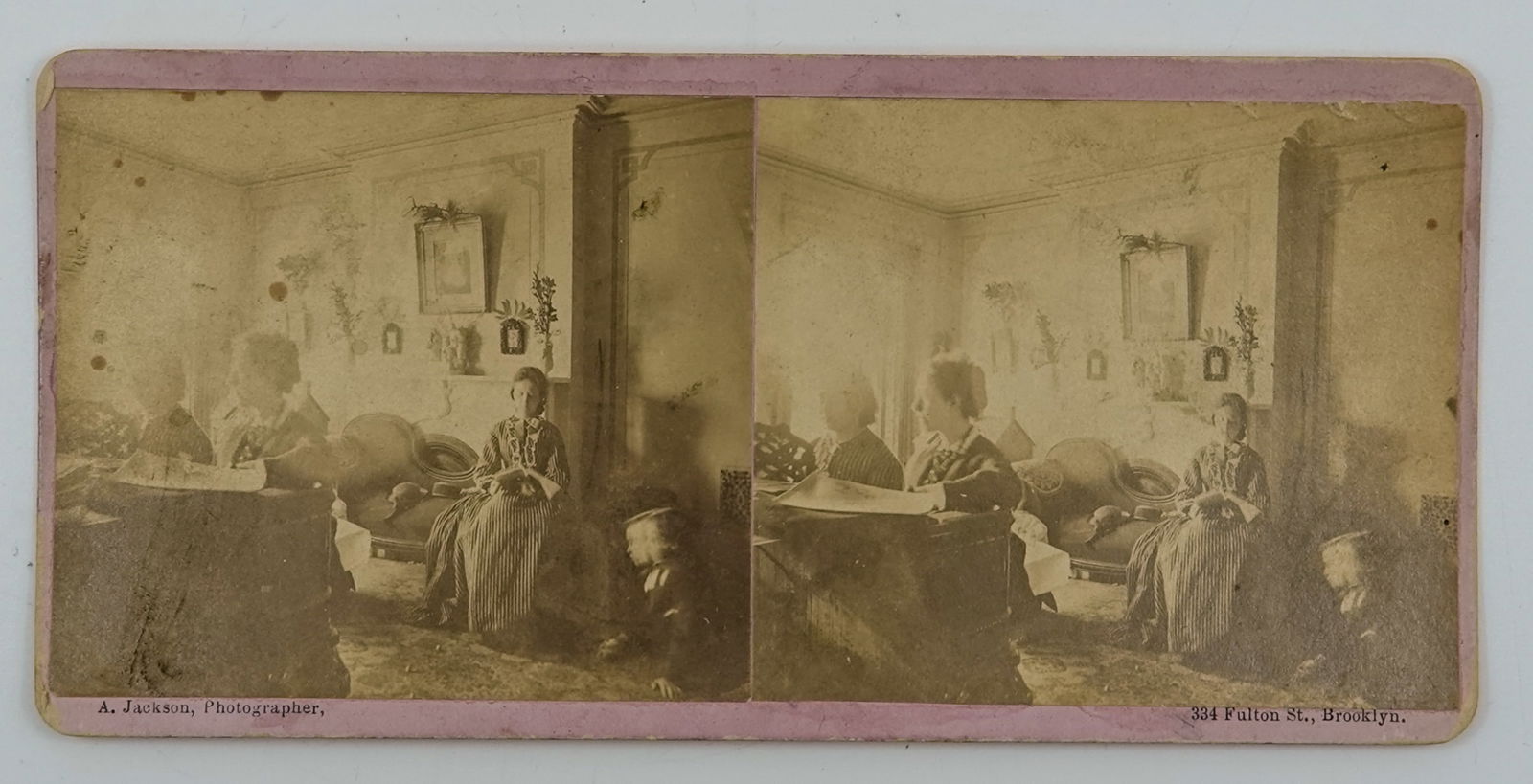 MISCELLANEOUS, Stereocard. Unusual image.: MISCELLANEOUS, Stereocard. A stereocard with a boy playing marbles. Much harder to find scene. A domestic scene depicting a parlor. Two women playing piano, one women on a settee who is reading, and a