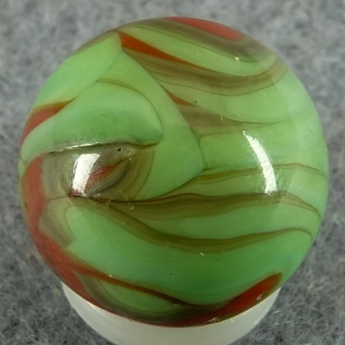 CHRISTENSEN AGATE COMPANY, Flame Swirl. 5/8". Near Mint(+) (8.9).: CHRISTENSEN AGATE COMPANY, Flame Swirl. Red flame swirls in light green. One manufacturing chip caused by an unmelted sand seed still present, but also several tiny hit sparkles. Cambridge OH, circa 1
