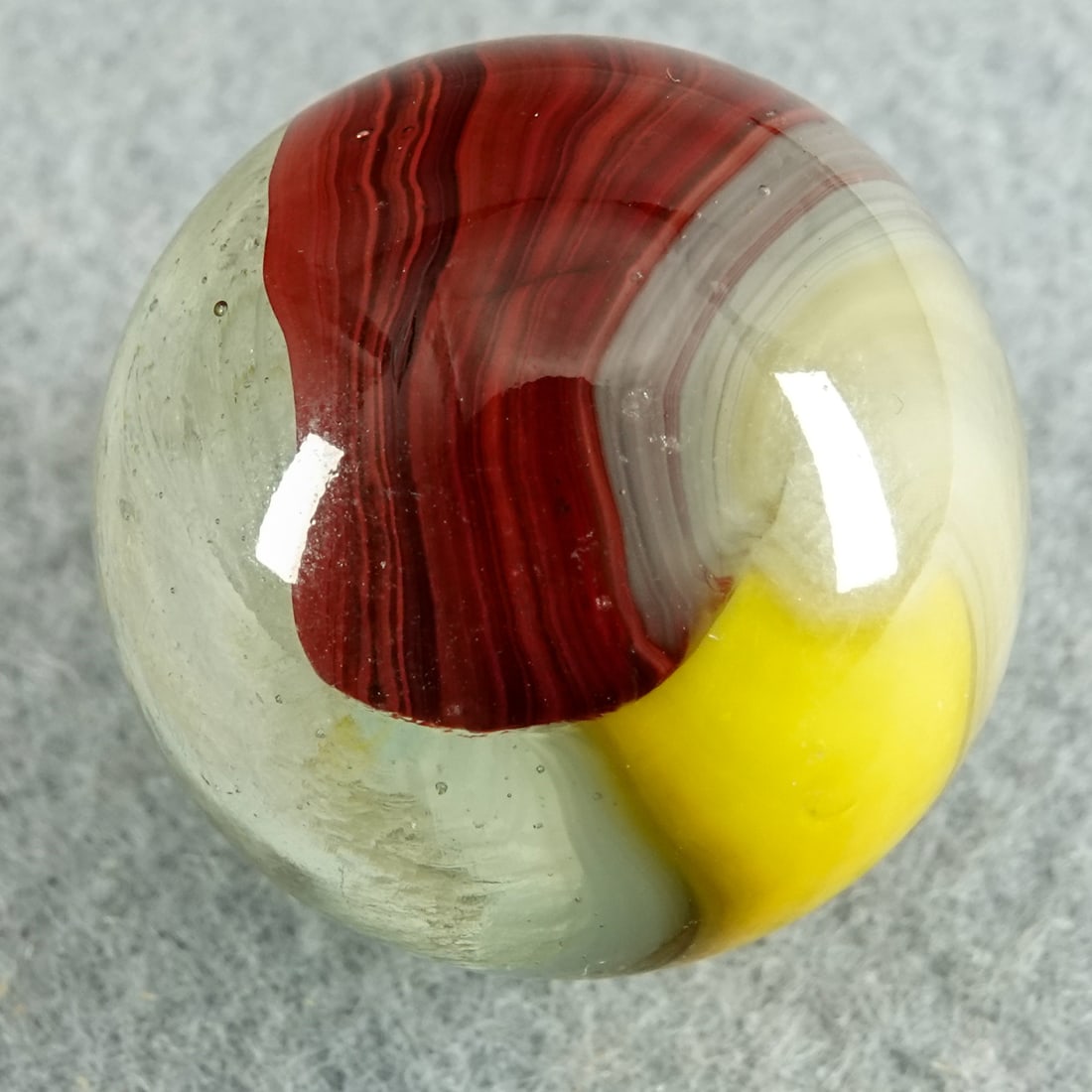 AKRO AGATE COMPANY, Patch Oxblood. 31/32". Near Mint(+) (8.9).: AKRO AGATE COMPANY, Patch Oxblood. Nice clear shooter Patch Oxblood. Base is one half clear and one half filled with wispy white. Large panels of oxblood and of yellow on the marble. One tiny sparkle