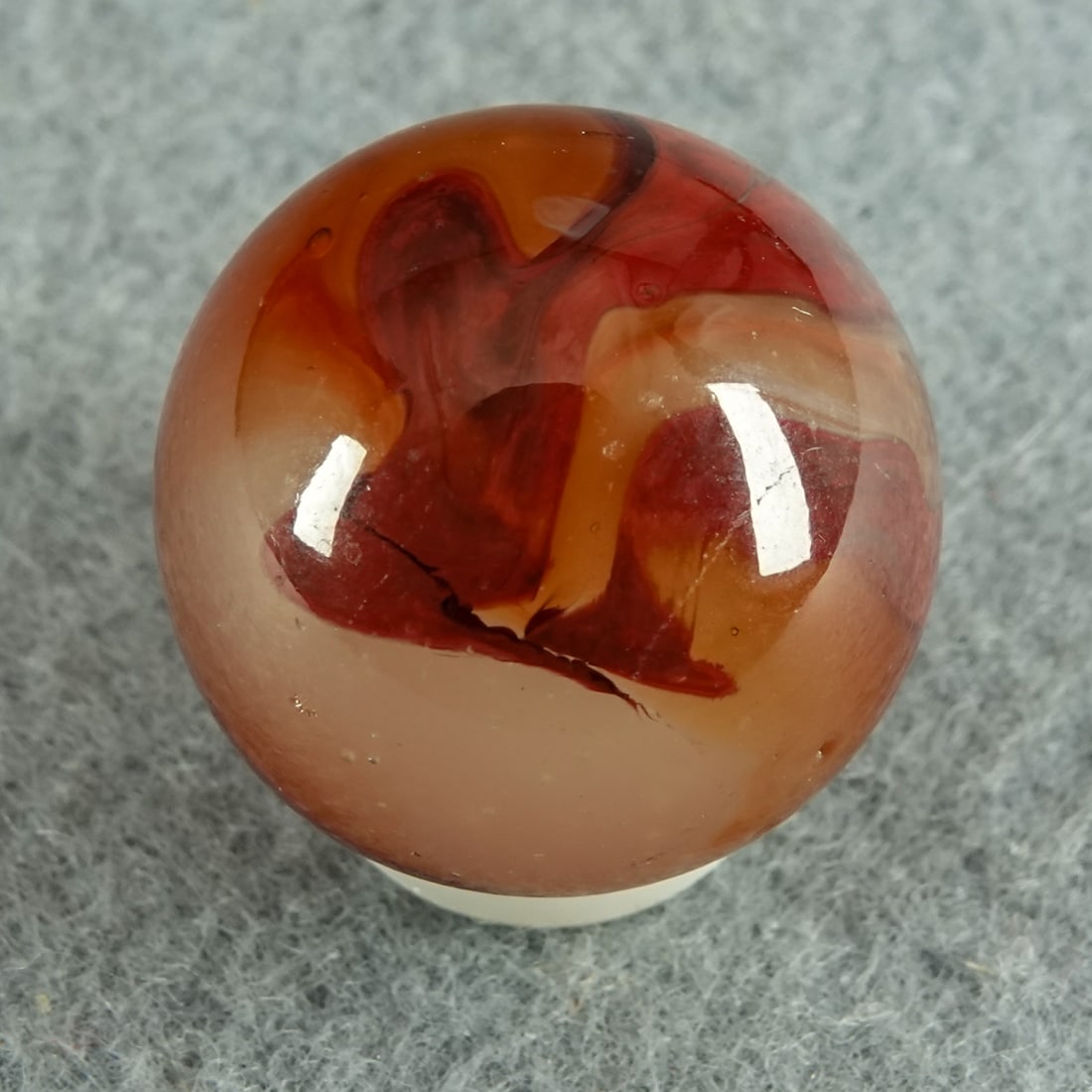AKRO AGATE COMPANY, Carnelian Oxblood. 25/32". Mint(-) (9.0).: AKRO AGATE COMPANY, Carnelian Oxblood. Milky white base. Surface swirls of semi-opaque reddish brown and loads of swirls of rich oxblood. Not fluorescent. Shooter. One small manufacturing melt pull sp