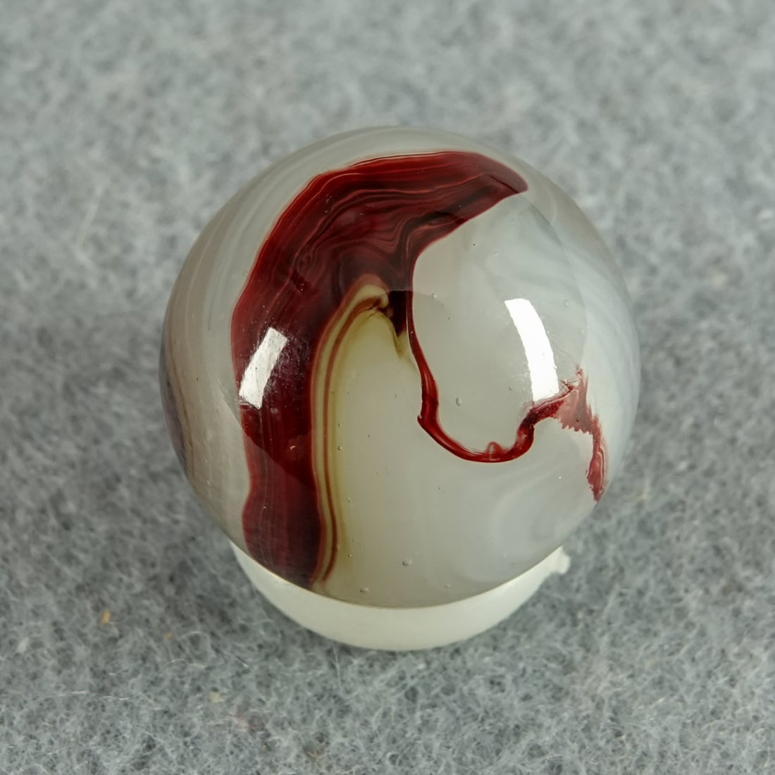 AKRO AGATE COMPANY, Silver Oxblood. 21/32". Mint (9.9).: AKRO AGATE COMPANY, Silver Oxblood. Translucent white base with milky white swirls and nice oxblood on the surface. Clarksburg WV, circa 1925-1935. 21/32". Mint (9.9).