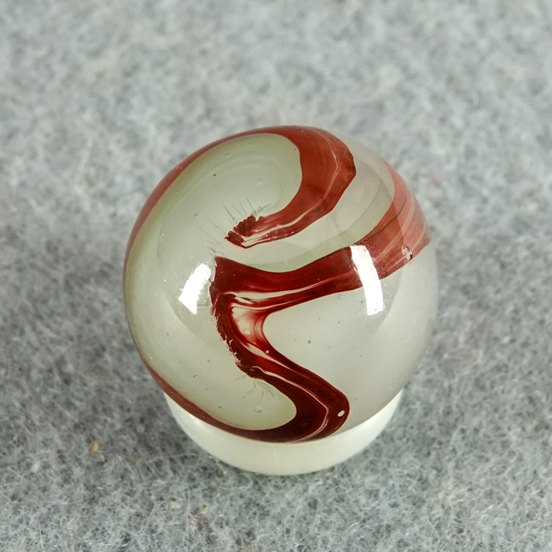 AKRO AGATE COMPANY, Silver Oxblood. 5/8". Near Mint(+) (8.9).: AKRO AGATE COMPANY, Silver Oxblood. Translucent white base with milky white swirls and nice oxblood on the surface. Very tin y chip. Clarksburg WV, circa 1925-1935. 5/8". Near Mint(+) (8.9).