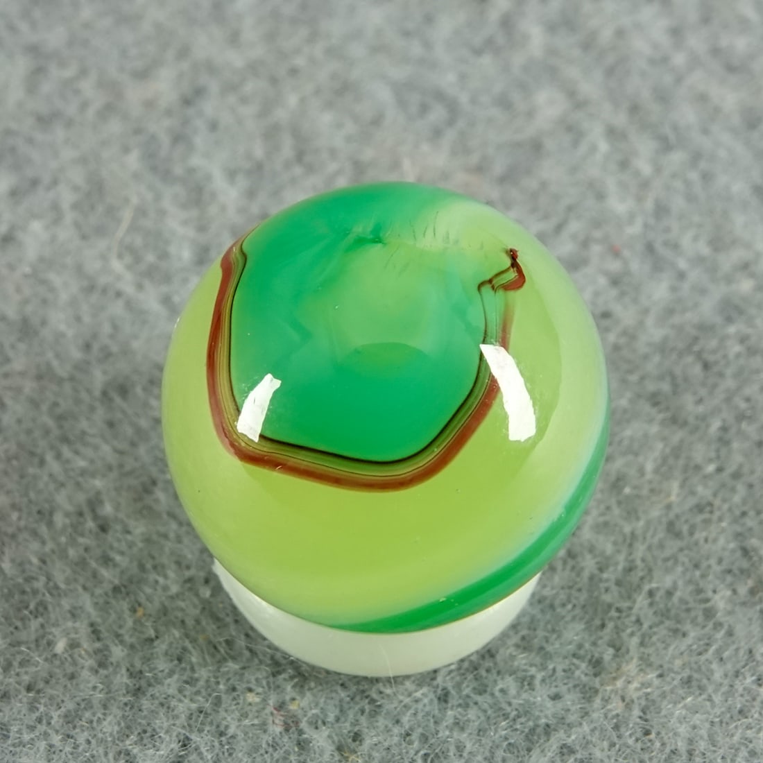 AKRO AGATE COMPANY, Limeade Oxblood. 5/8". Mint (9.9).: AKRO AGATE COMPANY, Limeade Oxblood. Fluorescent Ade base with translucent green swirls edged by oxblood. Clarksburg WV, circa 1925-1935. 5/8". Mint (9.9).