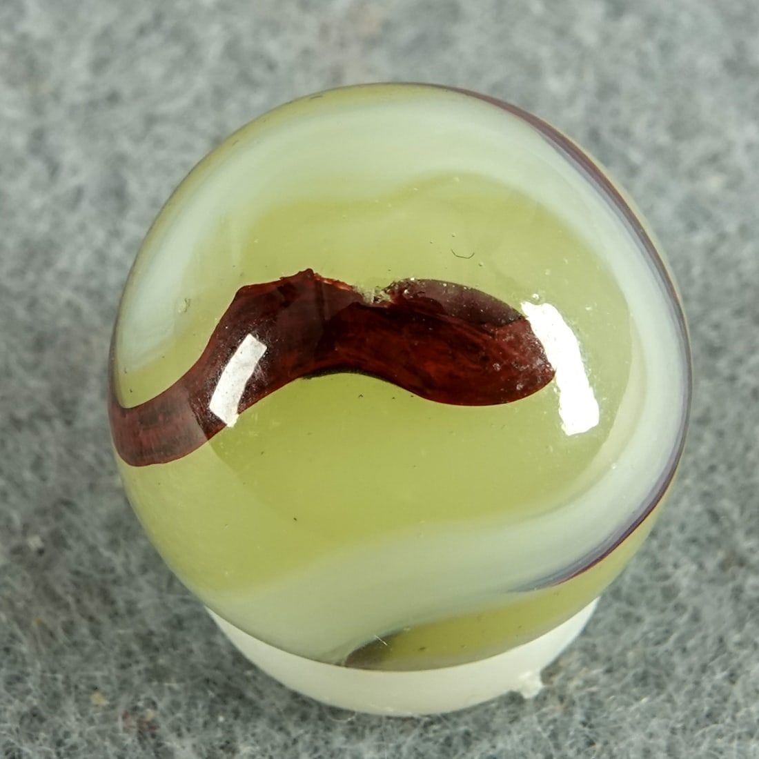 AKRO AGATE COMPANY, Lemonade Oxblood. 21/32". Near Mint(+) (8.9).: AKRO AGATE COMPANY, Lemonade Oxblood. Fluorescent Ade base with white and oxblood swirls. One very tiny chip. Clarksburg WV, circa 1925-1935. 21/32". Near Mint(+) (8.9).