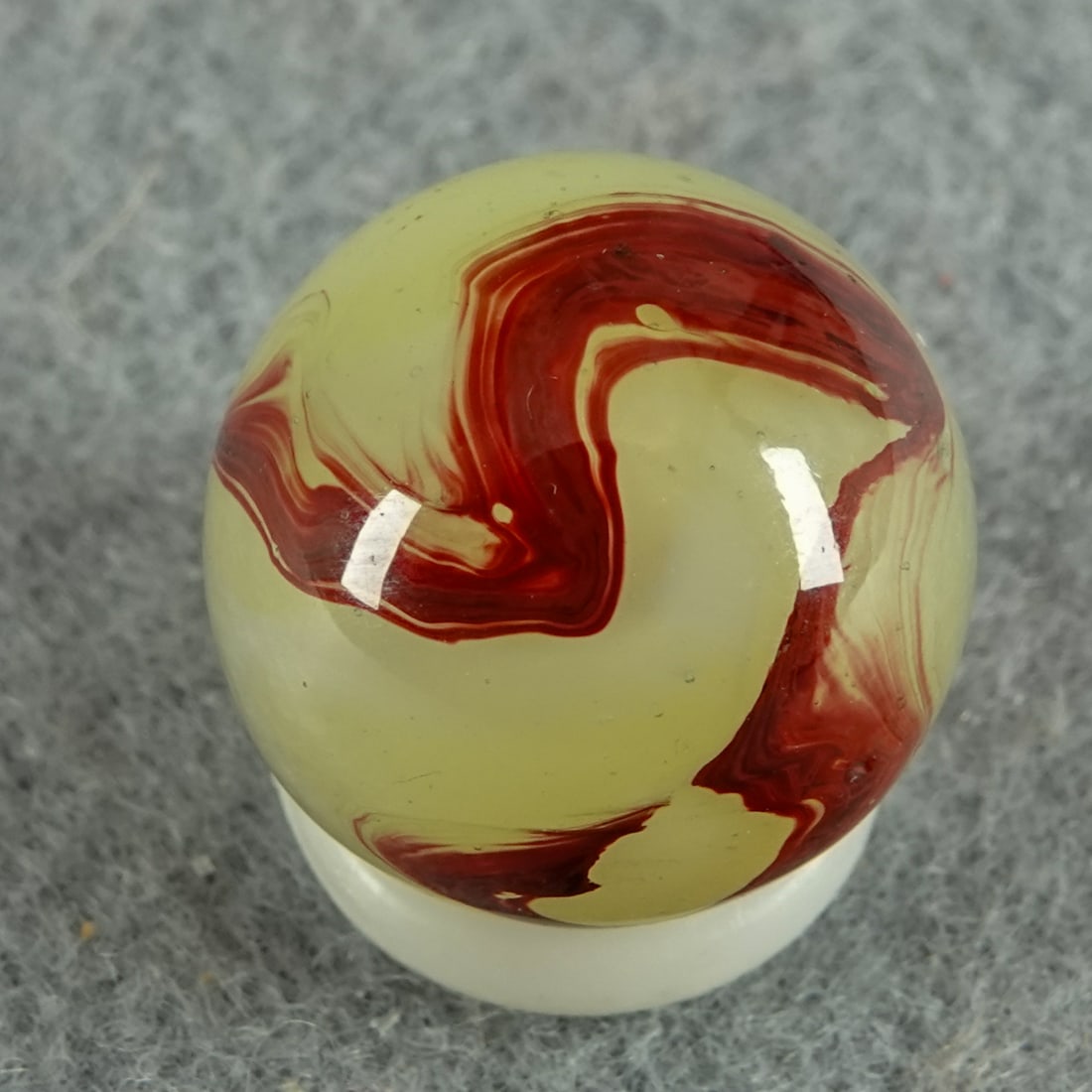 AKRO AGATE COMPANY, Lemonade Oxblood. 19/32". Mint (9.9).: AKRO AGATE COMPANY, Lemonade Oxblood. Fluorescent Ade base with white and oxblood swirls. One very tiny chip. Clarksburg WV, circa 1925-1935. Ex-collection Ralph Stagg. 19/32". Mint (9.9).