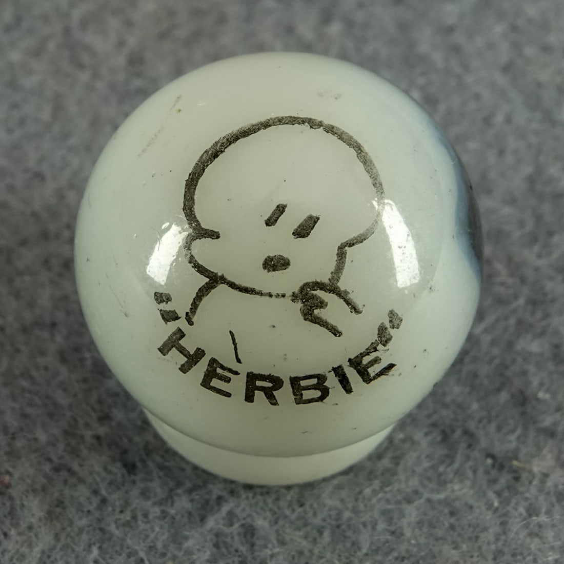PELTIER GLASS COMPANY, Character Marble (comic). Herbie. 21/32". Mint (9.9).: PELTIER GLASS COMPANY, Character Marble (comic). Herbie. Aventurine black patch, white base Peerless Patch. Average Transfer. Well centered. Ottawa IL, circa 1930-1935. 21/32". Mint (9.9).