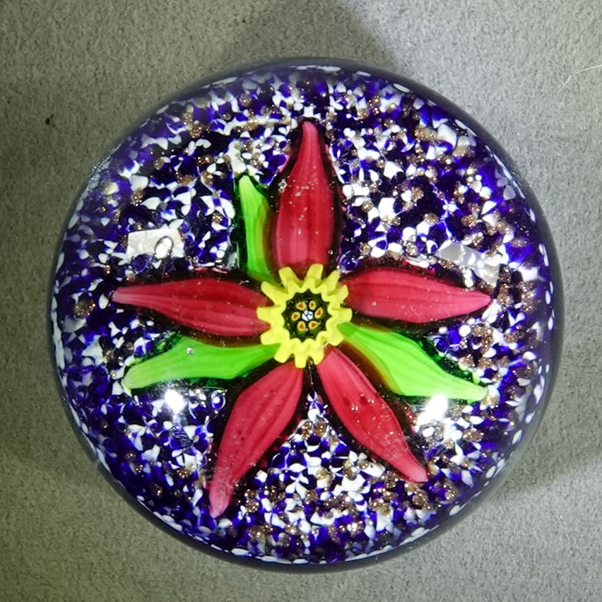 PAPERWEIGHT, Charles Kaziun Jr.: PAPERWEIGHT, Charles Kaziun Jr.. Miniature paperweight. Five petal flower with three leaves and yellow stamen on a jasper lutz ground. Middle pistil is a Kaziun "K" signature cane. 1-3/4" wide, 1-1/4"