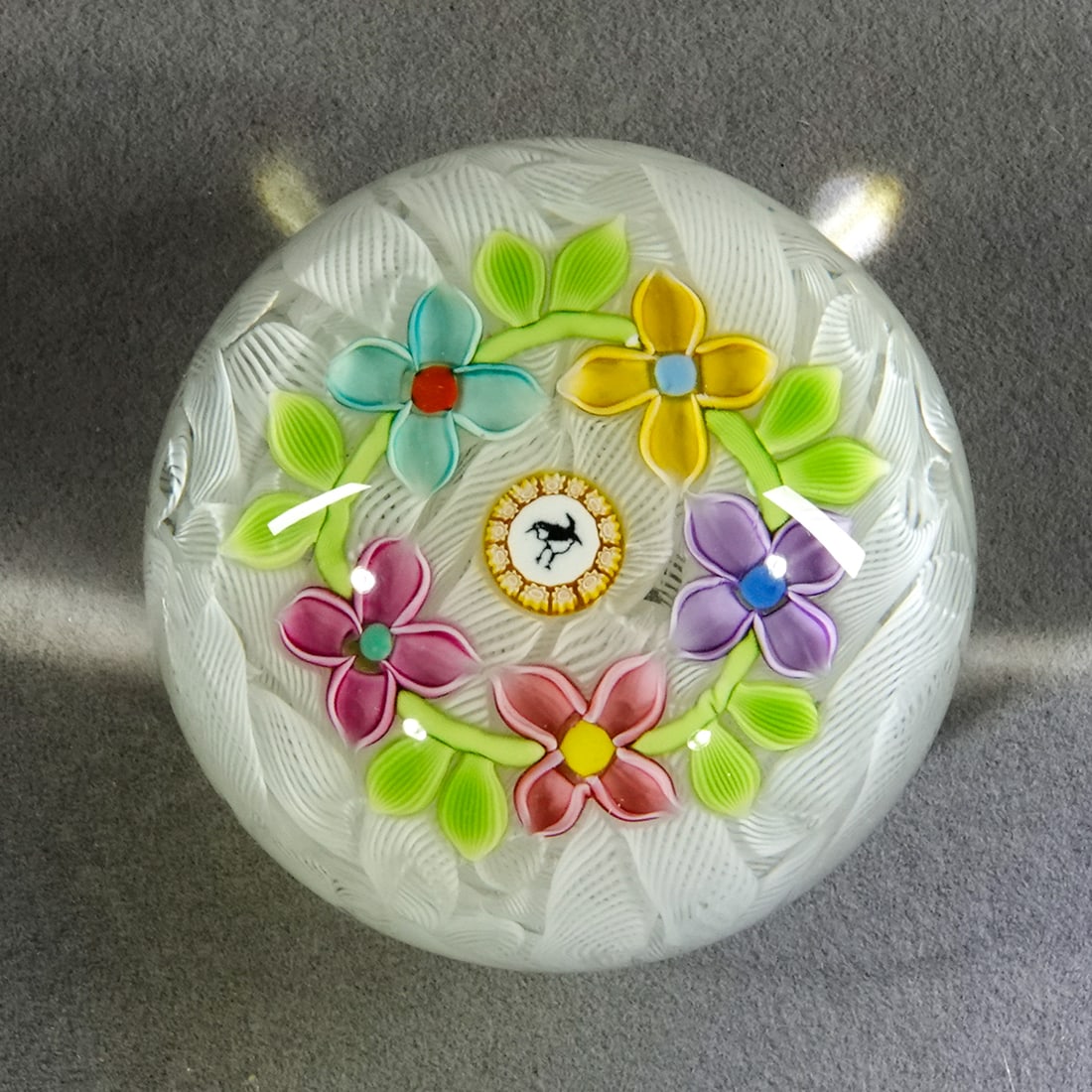 PAPERWEIGHT, Perthshire Paperweights.: PAPERWEIGHT, Perthshire Paperweights. Limited Edition paperweight. Upset muslin base. Floral wreath around a bird silhouette cane. Date cane in base "P 1997". Scratch numbered 59. 2-1/8" wide, 1-1/2"