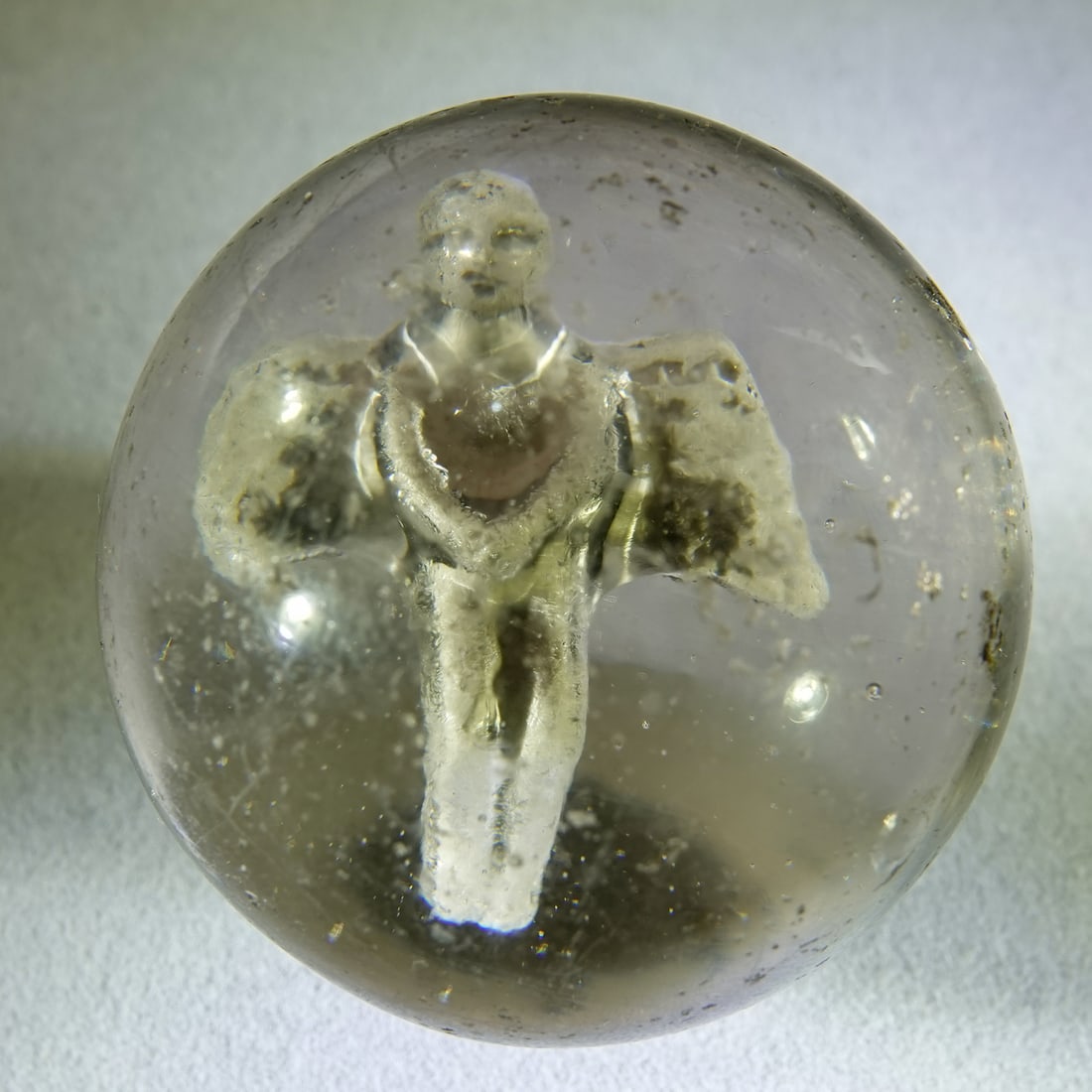SULPHIDE. Floating Angel. 1-11/16". Near Mint (8.6).: SULPHIDE. Figure is a Floating Angel. Hangs clasped over groin. Bent knees. The very tip of one wing is missing. Average detail. Well centered. Shallow air bubble on the from to the figure that does