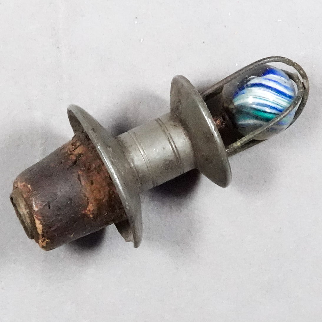 MISCELLANEOUS, Bottle Stopper. Antique Pewter with Onionskin.: MISCELLANEOUS, Bottle Stopper. Antique pewter bottle stopper with an antique German Onionskin in a cage as the operating piece. The top solder of the cage has disconnected. Small dent to the collar. N