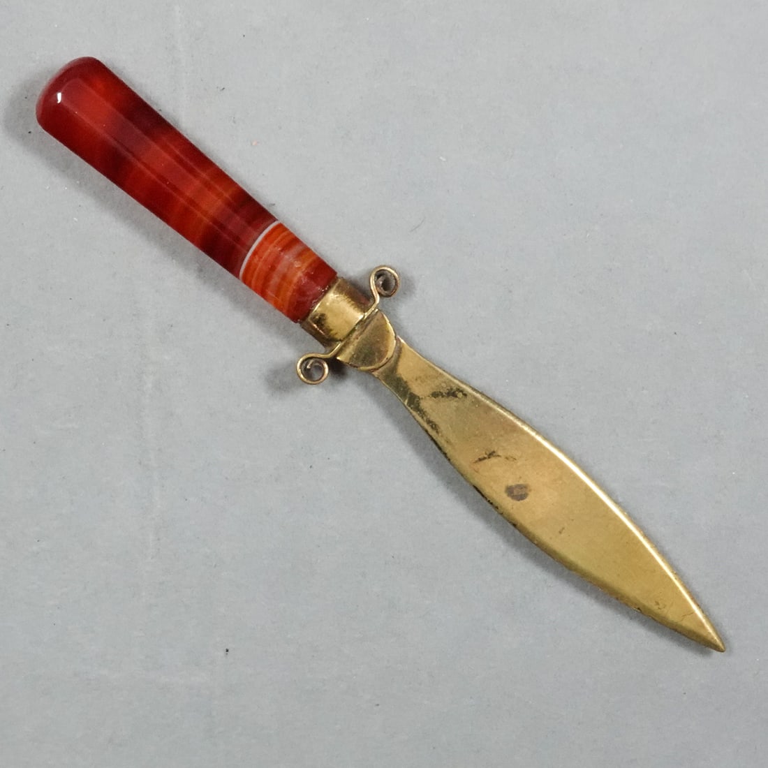 MISCELLANEOUS, Objet d'Vertu. Agate Letter Opener.: MISCELLANEOUS, Objet d'Vertu. Victorian Letter opener with an antique banded agate handle. Brass plade and fitting with scrolling. Nice handcut agate handle. Germany, circa 1850-1900. 5" long .