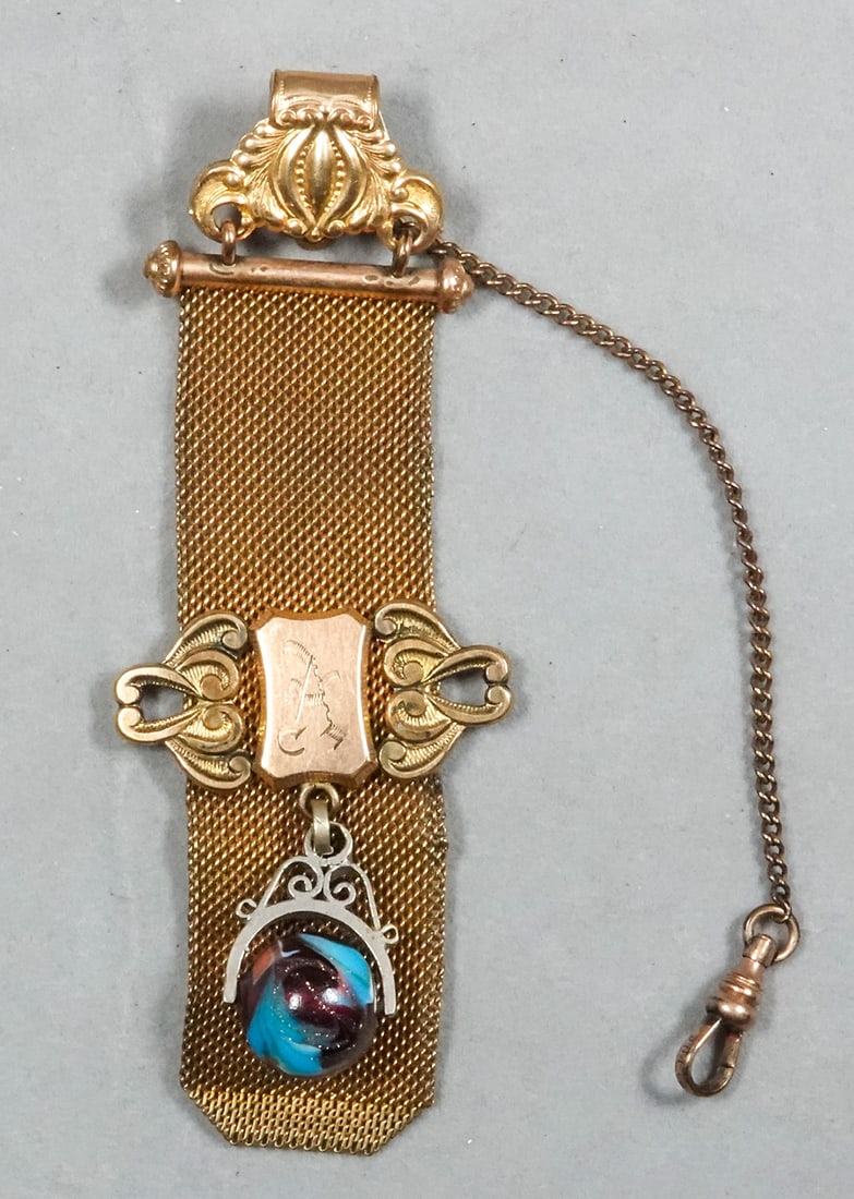 MISCELLANEOUS, Jewelry. Murano Bead and ribbon.: MISCELLANEOUS, Jewelry. Interesting pieces. Brass mesh ribbon on a clip, with a fitting holding a Murano glass bead so it spins. Monogrammed with an A. English (bead is Italian), circa 1860-1920.