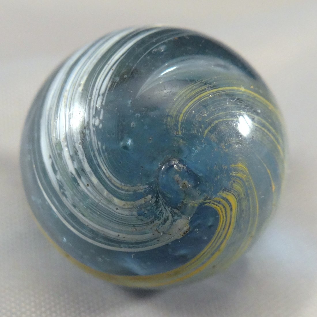 Marbles: Lot 8. OTHER HANDMADE, Indian. Mint (9.7).: Lot 8. OTHER HANDMADE, Indian. Transparent Indian. Transparent light blue base. Two bands of stretched color on the surface. One yellow, one white. Bands cover about eighty percent of the surface. Ger