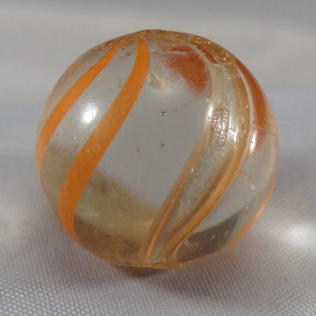Marbles: Lot 29. LUTZ, Banded. Near Mint(+) (8.9).: Lot 29. LUTZ, Banded. Transparent clear base. Four orange bands, two white-edged lutz bands. Blown air bubble on one band. Some scratches. Germany, circa 1860-1920. 21/32". Near Mint(+) (8.9).