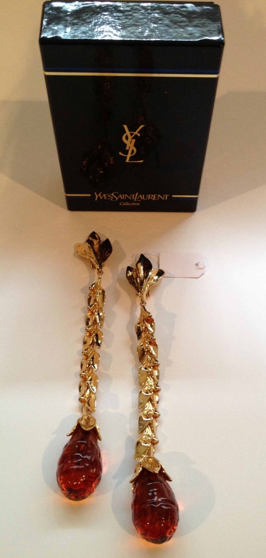 YVES SAINT LAURENT Longue paire de clips d'oreilles à m: YVES SAINT LAURENT Longue paire de clips d'oreilles à motif feuillage et perle de verre couleur ambre, longueur : 17 cm - Earclips in gold tone metal and amber glass pearl, length : 6.6'' (very good 