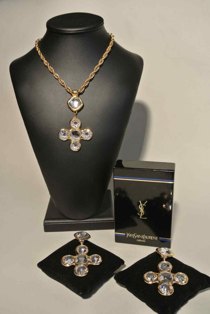 YVES SAINT LAURENT Demi parure en métal doré composée d: YVES SAINT LAURENT Demi parure en métal doré composée d'un collier croix et d'une paire de boucles d'oreilles au modèle, entièrement pavés de strass facettés - Longueur du collier : 30 cm et ha