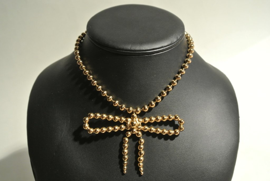 YVES SAINT LAURENT Rive Gauche Collier en métal doré co: YVES SAINT LAURENT Rive Gauche Collier en métal doré composé de boules formant un noeud - Longueur totale: 39cm "Bow" gold tone metal necklace - Totale Length: 15,7in.