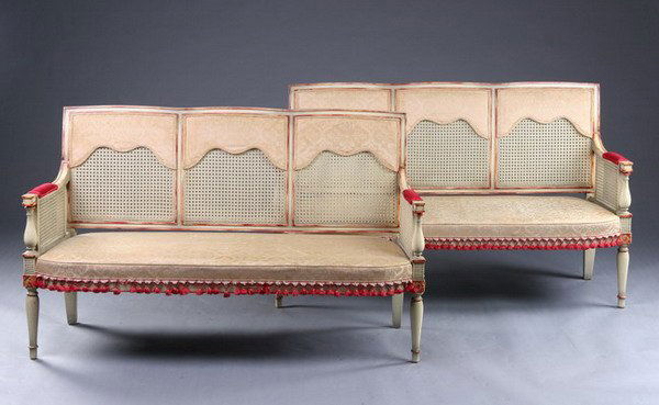 PAIR LOUIS XVI STYLE PAINTED SETTEES, 20th century: PAIR LOUIS XVI STYLE PAINTED SETTEES, 20th century. Rectangular crest rail above three caned panels with upholstered valences; conforming cream painted frame with brushed red accents; vase-turned arm