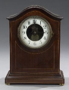 AN ENGLISH INLAID MAHOGANY ELECTRIC MANTEL CLOCK,: AN ENGLISH INLAID MAHOGANY ELECTRIC MANTEL CLOCK, by Eureka, model no. 4440, circa 1910. The arched case with projecting molded cornice and plinth base on brass feet - 11 3/4 in. high.