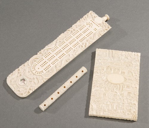 A CHINESE CARVED IVORY CRIBBAGE BOARD.: A CHINESE CARVED IVORY CRIBBAGE BOARD. Rectangular, painted with a landscape medallion and carved allover with coiling dragons; together with a Chinese card box and two needle cases (4) - 7 5/8 in. th