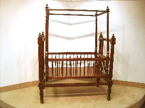 AN ANGLO-INDIAN REGENCY STYLE CRIB OF EXOTIC WOOD: AN ANGLO-INDIAN REGENCY STYLE CRIB OF EXOTIC WOOD, Early 19th century. The two-part structure composed of a rocking four poster bed, enclosed with turned spindles within a stationary similar four post