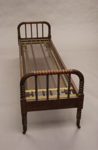 AN AMERICAN MIXED WOOD DAY BED, 19th century. With: AN AMERICAN MIXED WOOD DAY BED, 19th century. With matching spool turned legs with casters and spring insert for support of mattress (lacking mattress) - 27 in x 79 in x 23 3/4 in.