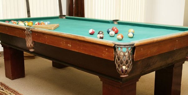 A POOL TABLE. - 32 in. x 98 in. x 50.: A POOL TABLE, together with pool table accessories including cue racks, cues, bridge, two sets of balls, brushes, score keepers, etc. - 32 in. x 98 in. x 50.