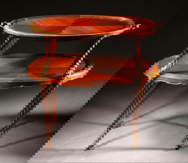 A LOUIS XV STYLE MAHOGANY TWO TIER SERVING TABLE,: A LOUIS XV STYLE MAHOGANY TWO TIER SERVING TABLE, Early 20th century. Having two oval surfaces with parquetry inlay, gilt metal mounts and curving cabriole legs on casters. - 31 1/4 in. x 31 1/4 in. x