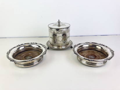 ENGLISH VICTORIAN SILVER-PLATED BISCUIT BARREL BY ROBINSON & CO., AND PAIR SILVER-PLATED WINE: ENGLISH VICTORIAN SILVER-PLATED BISCUIT BARREL BY ROBINSON & CO., AND PAIR SILVER-PLATED WINE COASTERS WITH TURNED TREEN BASES. Cylindrical biscuit box has hinged cover, chased decoration, and