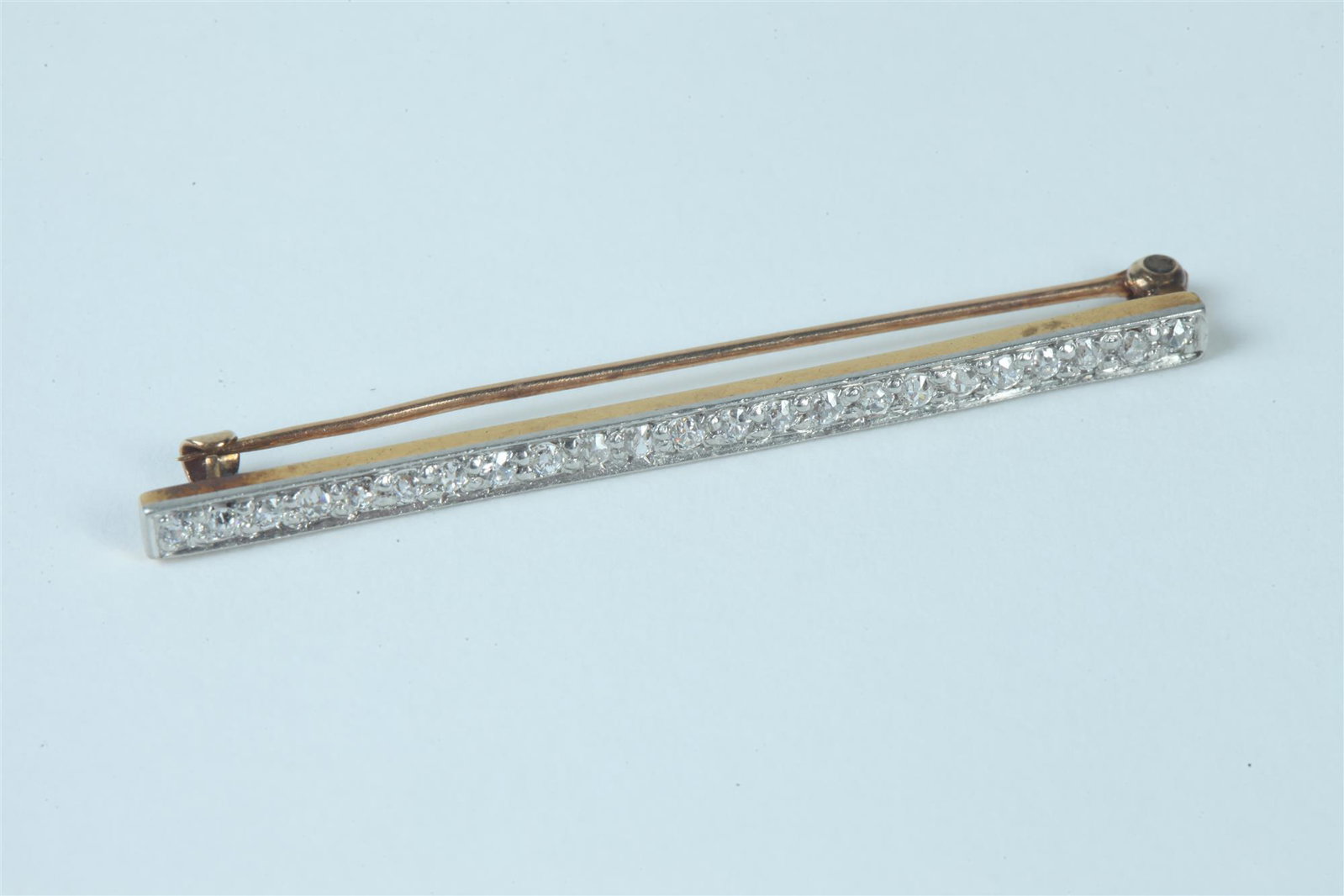 EDWARDIAN PLATINUM-ON-YELLOW GOLD AND DIAMOND BAR PIN.: EDWARDIAN PLATINUM-ON-YELLOW GOLD AND DIAMOND BAR PIN. circa 1900, Row of 23 matched old European cut round diamonds together weighing app. .91 ct. L: 2 1/4 in.