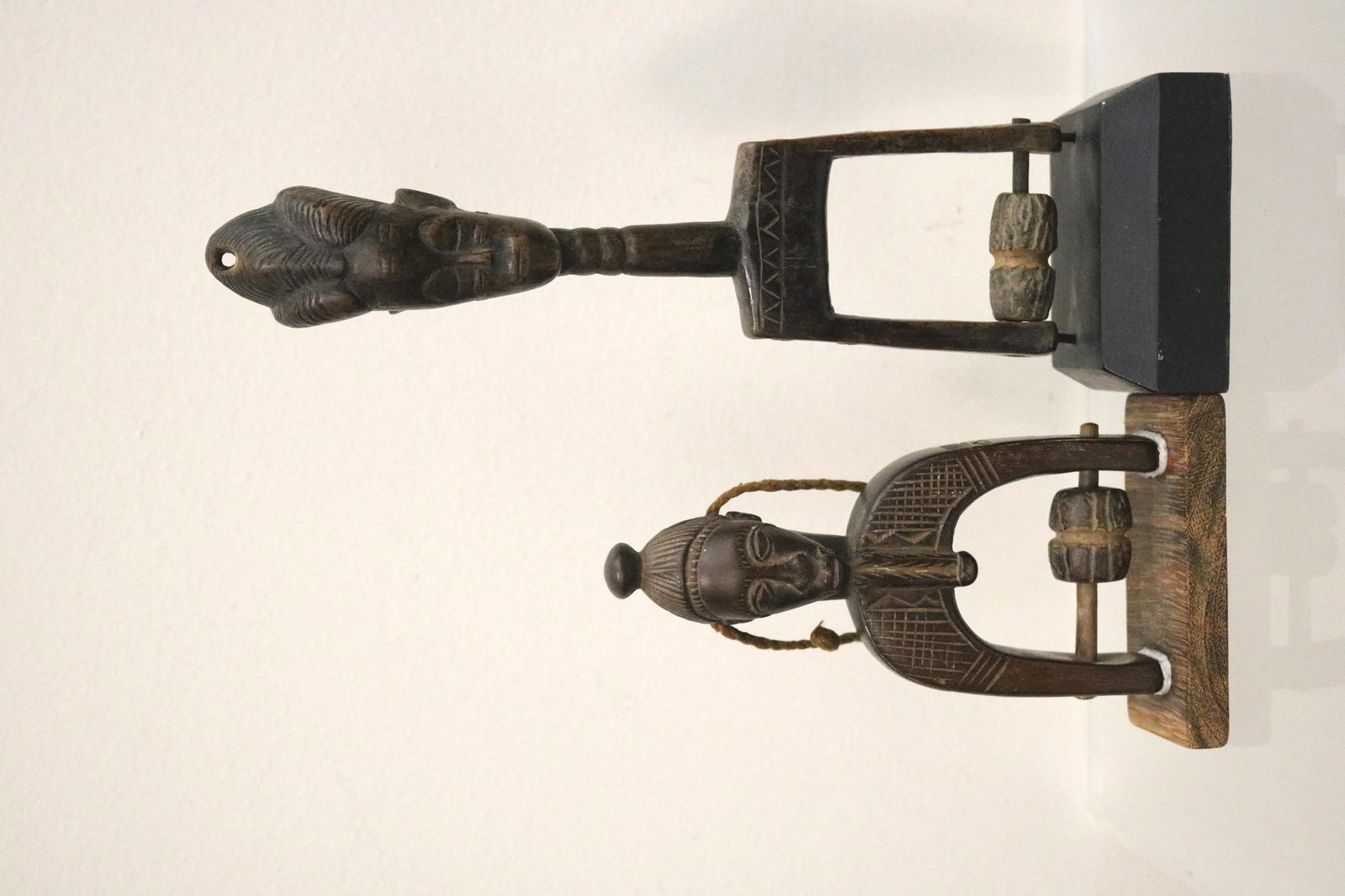 TWO BAULE PEOPLES IVORY COAST HEDDLEY PULLEYS, Early-to-mid 20th century. - 8.25 inches; base: 1: TWO BAULE PEOPLES IVORY COAST HEDDLEY PULLEYS, Early-to-mid 20th century. Decorated patinated wooden heddley pulleys from the Baule People in Ivory Coast. Both are presented on appropiate stands. - 8.
