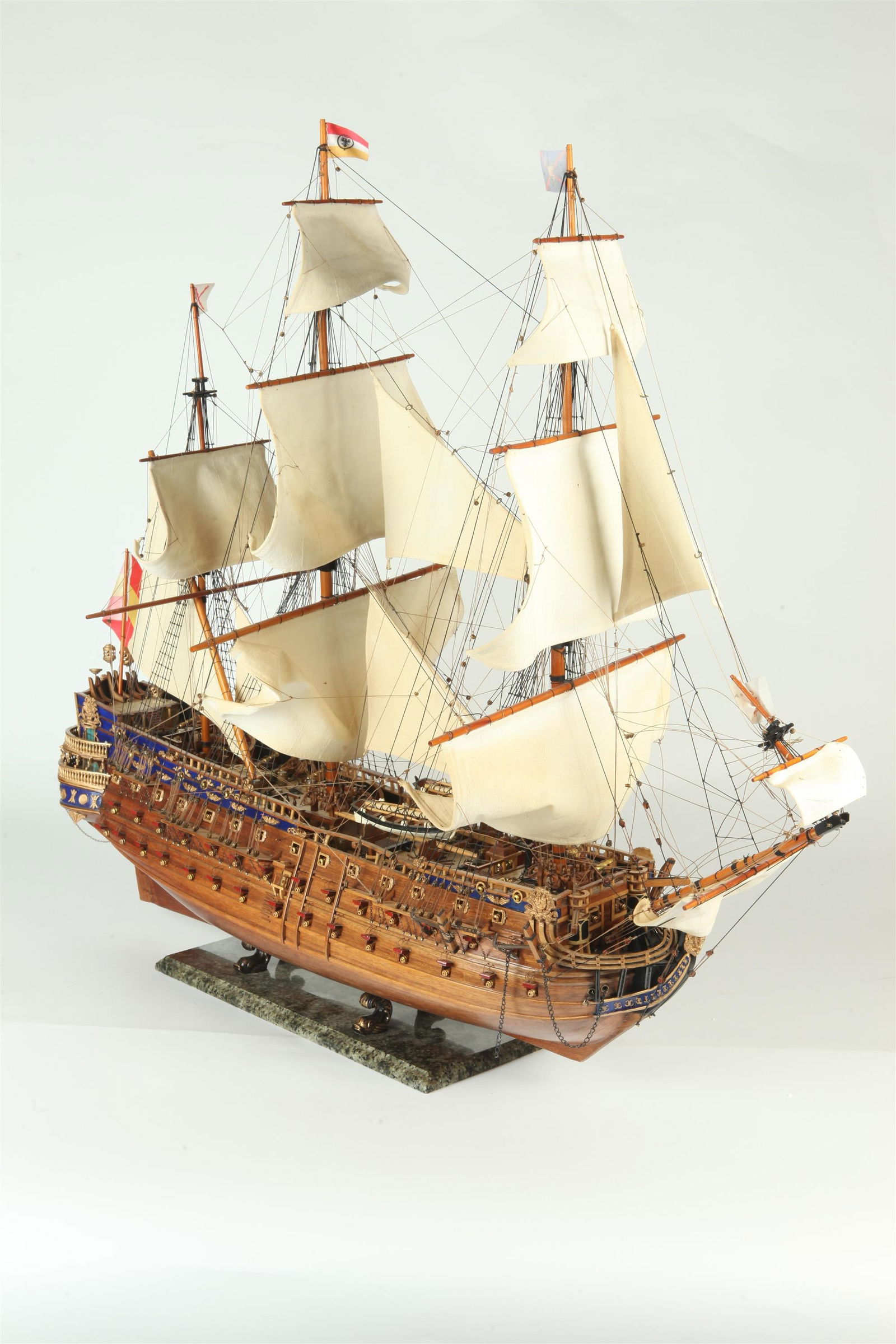 EALRY TO MID 20TH CENTURY CARVED AND PAINTED WOODEN MODEL OF THREE MASTED WARSHIP. - H: 32"; L: 36",: EALRY TO MID 20TH CENTURY CARVED AND PAINTED WOODEN MODEL OF THREE MASTED WARSHIP. Elaborate rigging; cloth sails; fully fitted with finely carved accessories and brass cannons; raised on marble plin