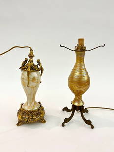 TWO ART GLASS TABLE LAMP BASES. - Taller, H: 13", overall.: TWO ART GLASS TABLE LAMP BASES.  One, gold favrile with threaded decoration; other, Steuben with cream ground with stylized gold branches and leaves; metal mounts. - Taller, H: 13", overall.