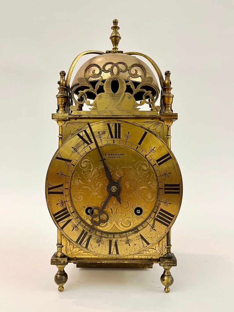 SCOTTISH BRASS LANTERN CLOCK BY R. STEWART, GLASCOW,: SCOTTISH BRASS LANTERN CLOCK BY R. STEWART, GLASCOW. (face signed). Pierced crest with double dolphin motif over scroll-engraved face with black Roman numerals; chiming movement. H: 15".