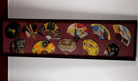 11 VINTAGE FRENCH ADVERTISING LITHOGRAPHED PAPER FOLDING FANS ARRANGED IN A SHADOW BOX FRAME.