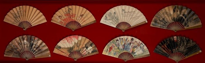 EIGHT VINTAGE FOLDED PAPER FANS DEPICTING FIGURES IN PERIOD COSTUME IN VARIOUS SETTINGS MOUNTED IN A