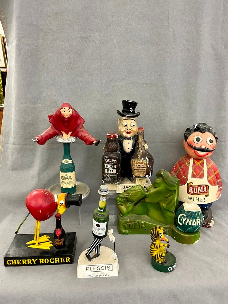 SEVEN VINTAGE FRENCH FIGURAL BEVERAGE ITEMS. - Tallest, 17 in.: SEVEN VINTAGE FRENCH FIGURAL BEVERAGE ITEMS. Items including Cinzano zebra, SPA acrobat, Cherry Rocher bird, Rome Wines waiter, Cynar lady, and Jacquin's man in top hat. - Tallest, 17 in.