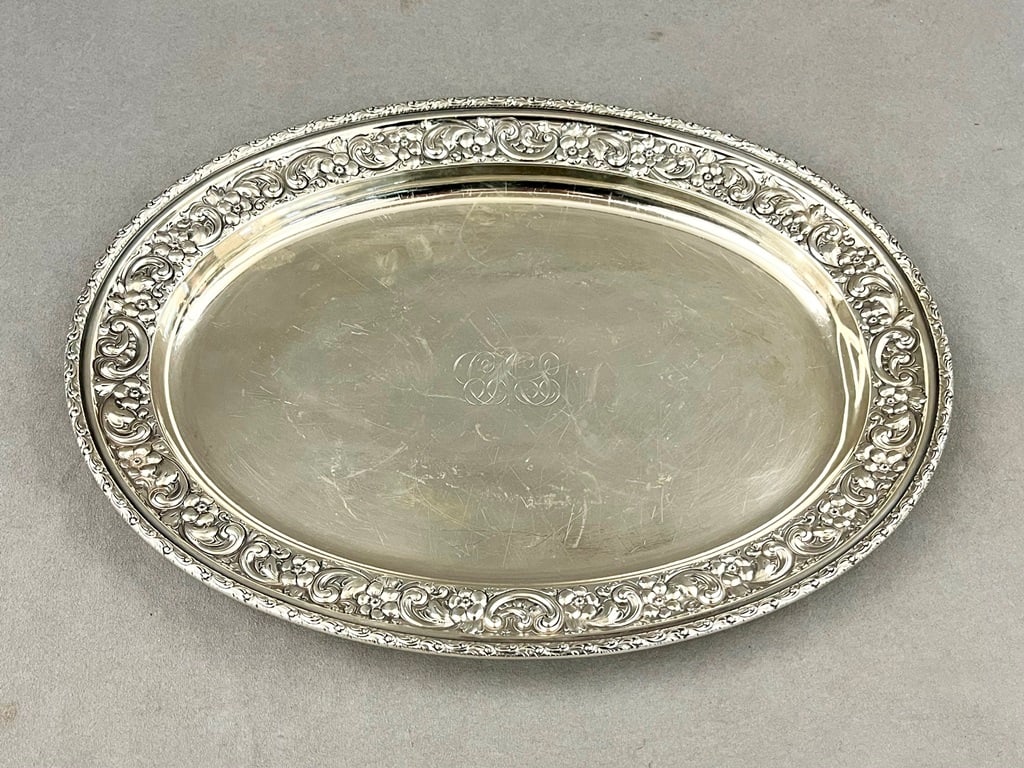 DOMINICK & HAFF STERLING SILVER OVAL PLATTER, late 19th century. - L: 14 in. Wt: 27 troy oz.: DOMINICK & HAFF STERLING SILVER OVAL PLATTER, late 19th century. made 1886. Floral and scroll repousse border; monogrammed. - L: 14 in. Wt: 27 troy oz.Property of Visionary Architect Arthur Cotton Moo